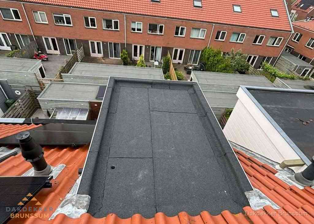 Plat dak met bitumen bedekking naast dakkapel in Brunssum
