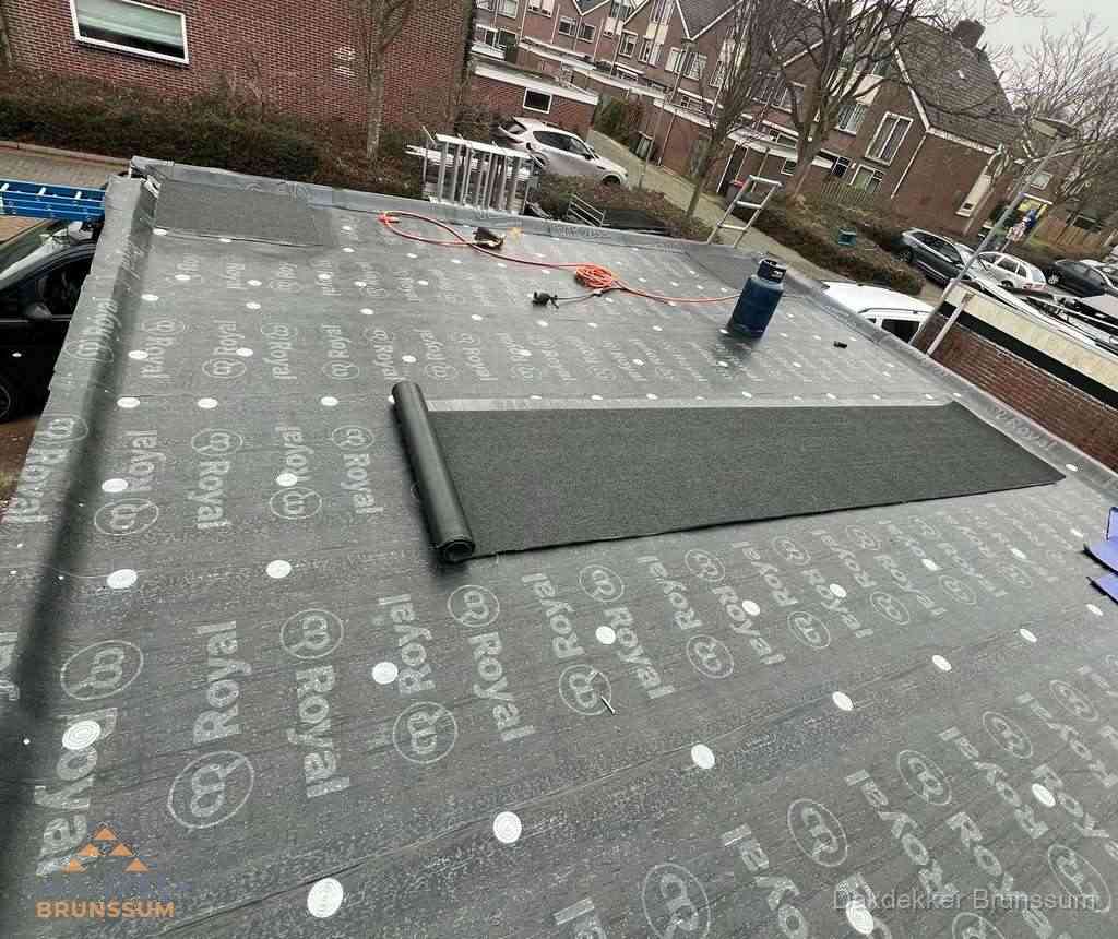 Dakdekker aan het werk met gasbrander op plat bitumen dak in Brunssum